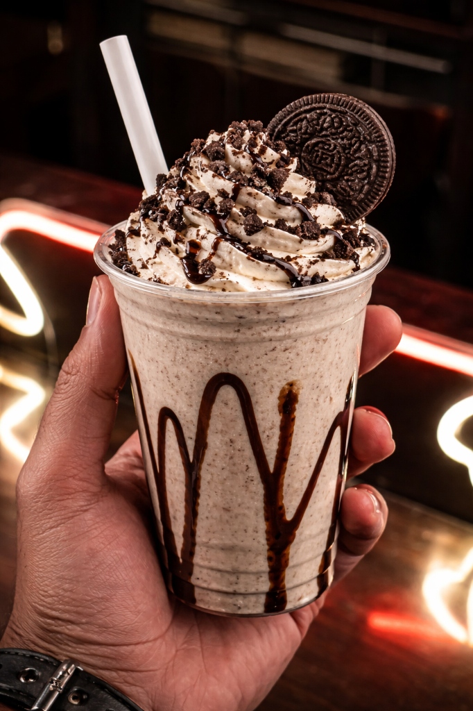 Thick Oreo milkshake with cookie crumbles and whipped cream topped with whole Oreo cookie